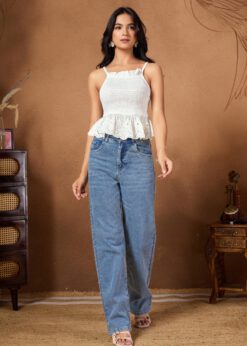 White sleeveless smocked crop top with intricate eyelet lace detailing paired with blue jeans