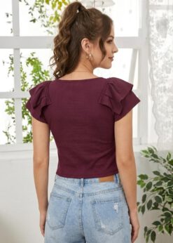A woman wearing a wine-coloured, ribbed, short-sleeve top with a sweetheart neckline and centre-ruched detail