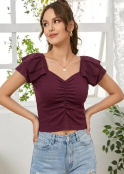 A woman wearing a wine-coloured, ribbed, short-sleeve top with a sweetheart neckline and centre-ruched detail